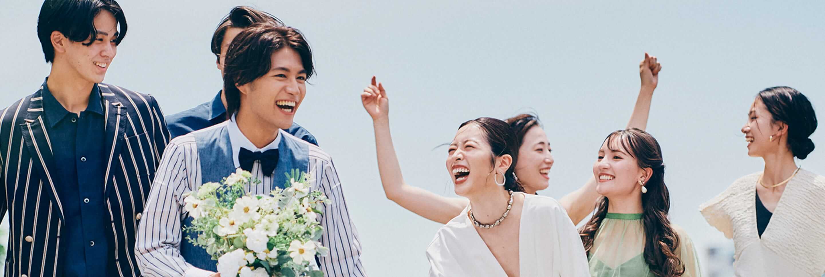 新郎新婦が仲間たちに囲まれながら、笑顔で水上テラスに向かう姿。