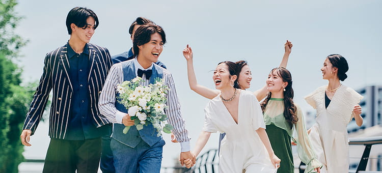 新郎新婦が仲間たちに囲まれながら、笑顔で水上テラスに向かう姿。